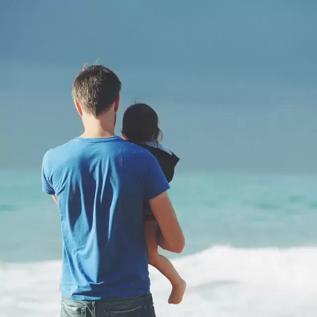 a father holding his child near the ocean