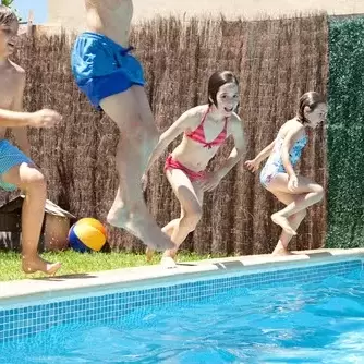 four children jumping into a swimming pool