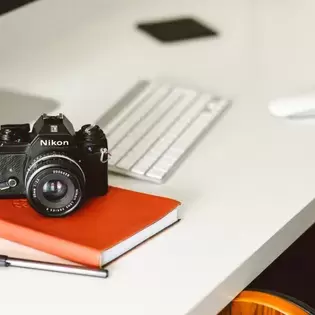 An SLR camera on a desk next to a keyboard.
