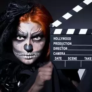 Goth woman with red hair holding a movie action board.