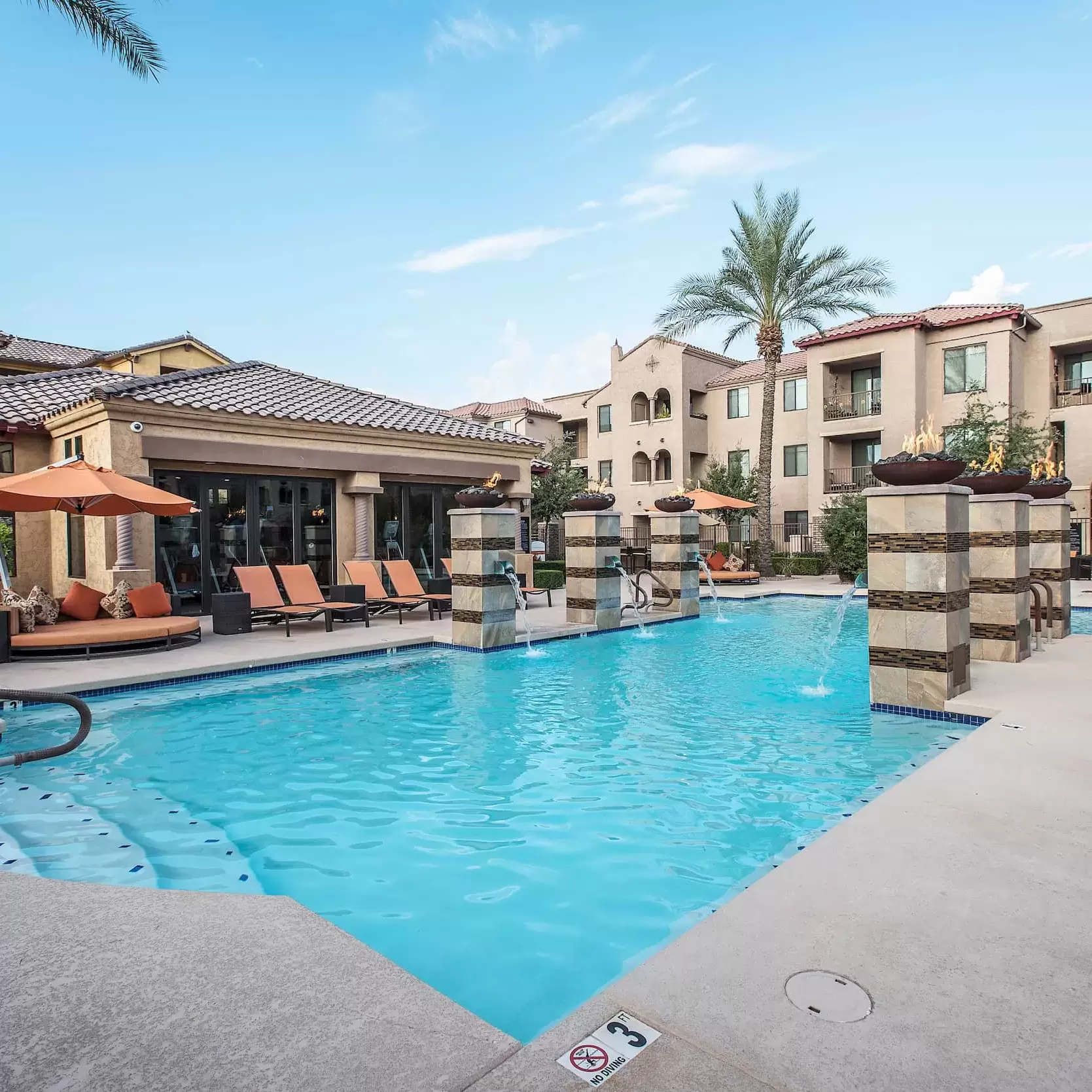 A pool surrounded by lounge chairs and palm trees at Liv Avenida in Chandler, Az.