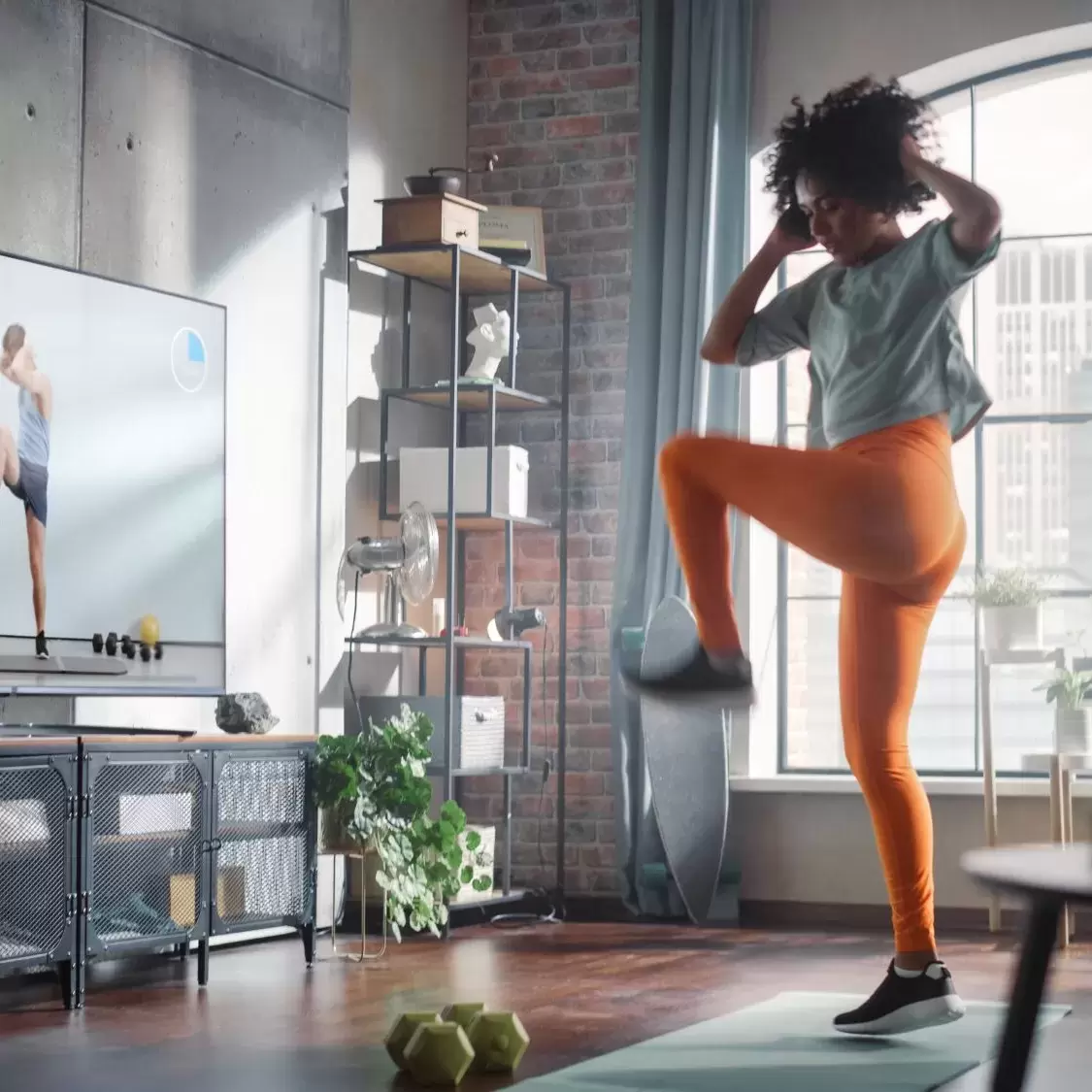 A woman exercising in her living room while following a workout on her television.
